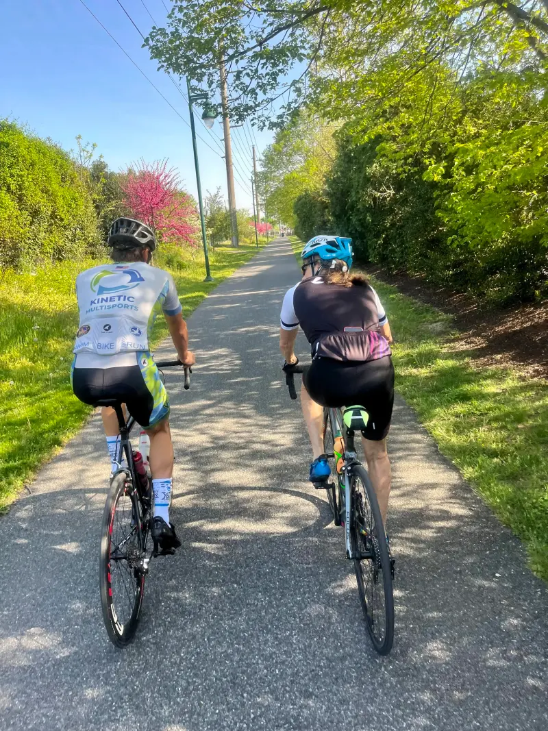 Two cyclists on a tree-lined path