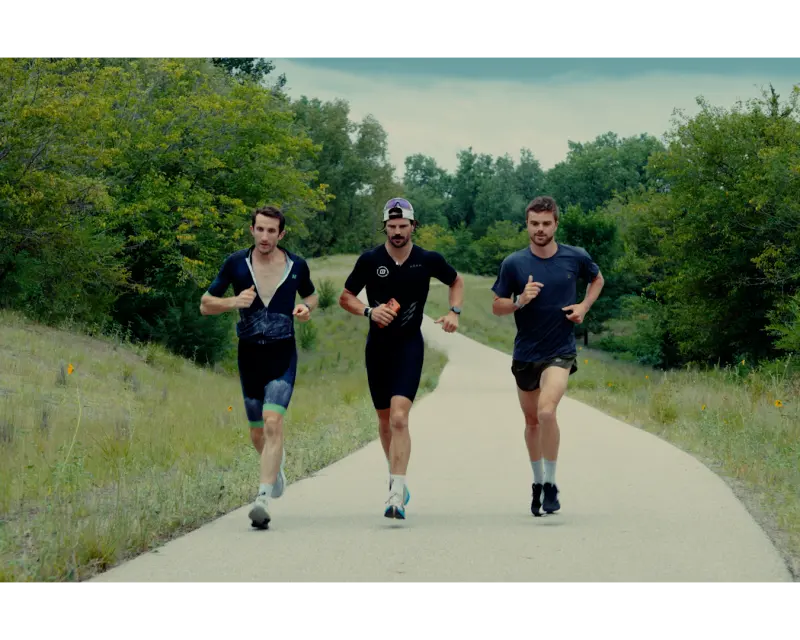 Three athletes running a trail together