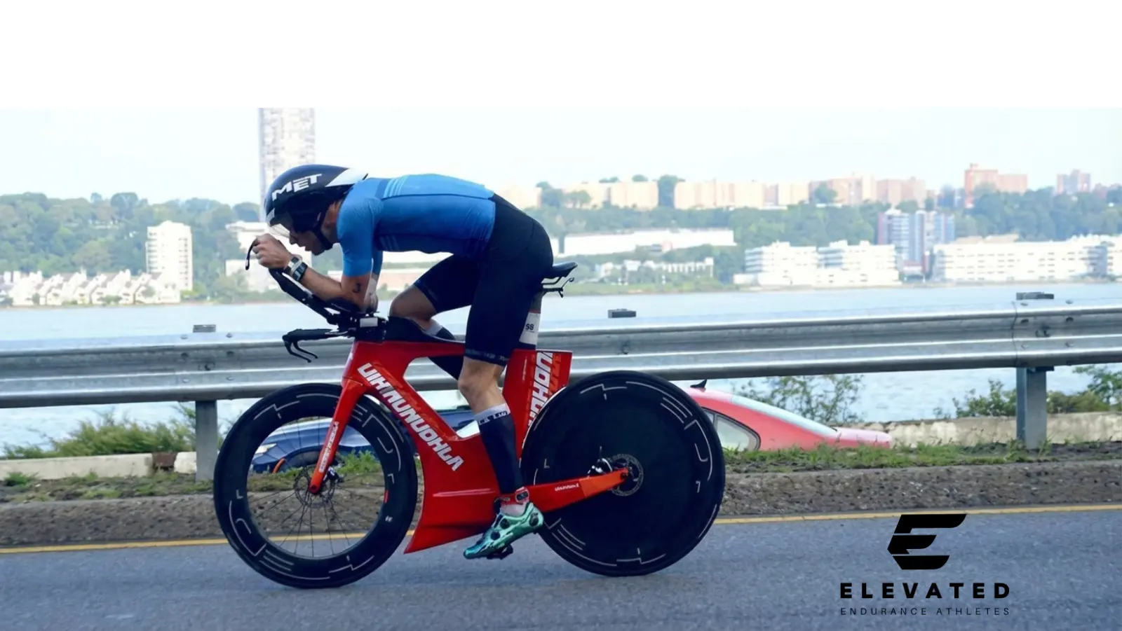 Elevated Endurance athlete racing a time trial bike along the water
