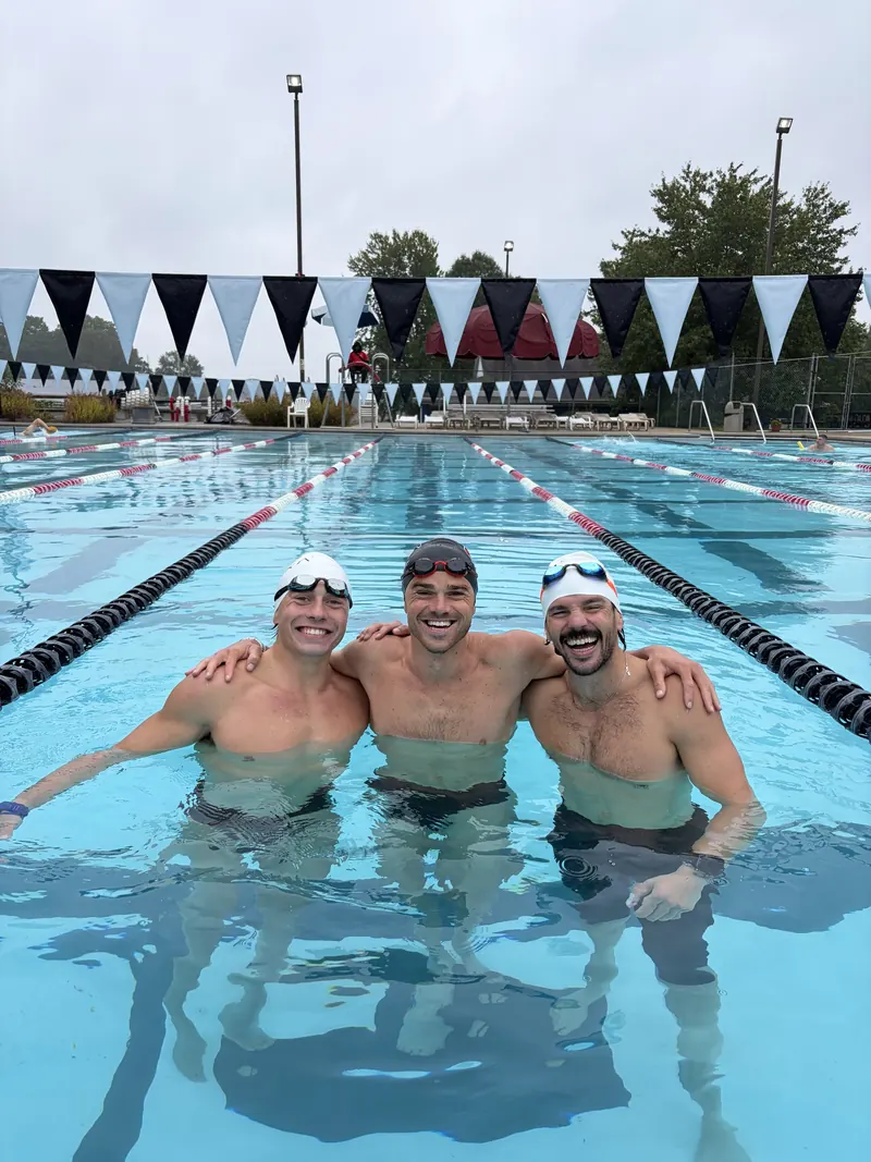 Luke Hopkins, Coach Brett Saunders and Dan Churchhill laughing together in an outdoor pool lane